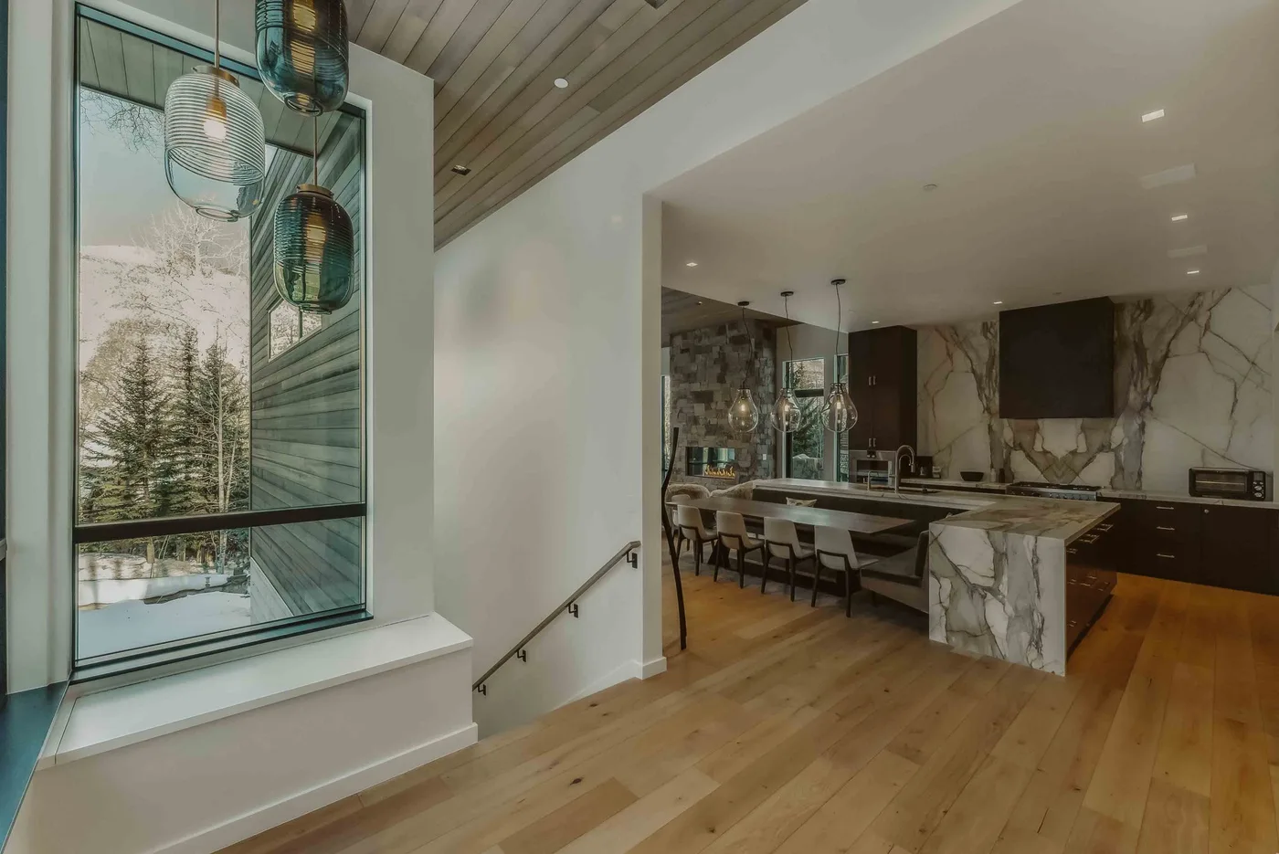 Una cocina y comedor abiertos con una ventana grande y lámparas colgantes.