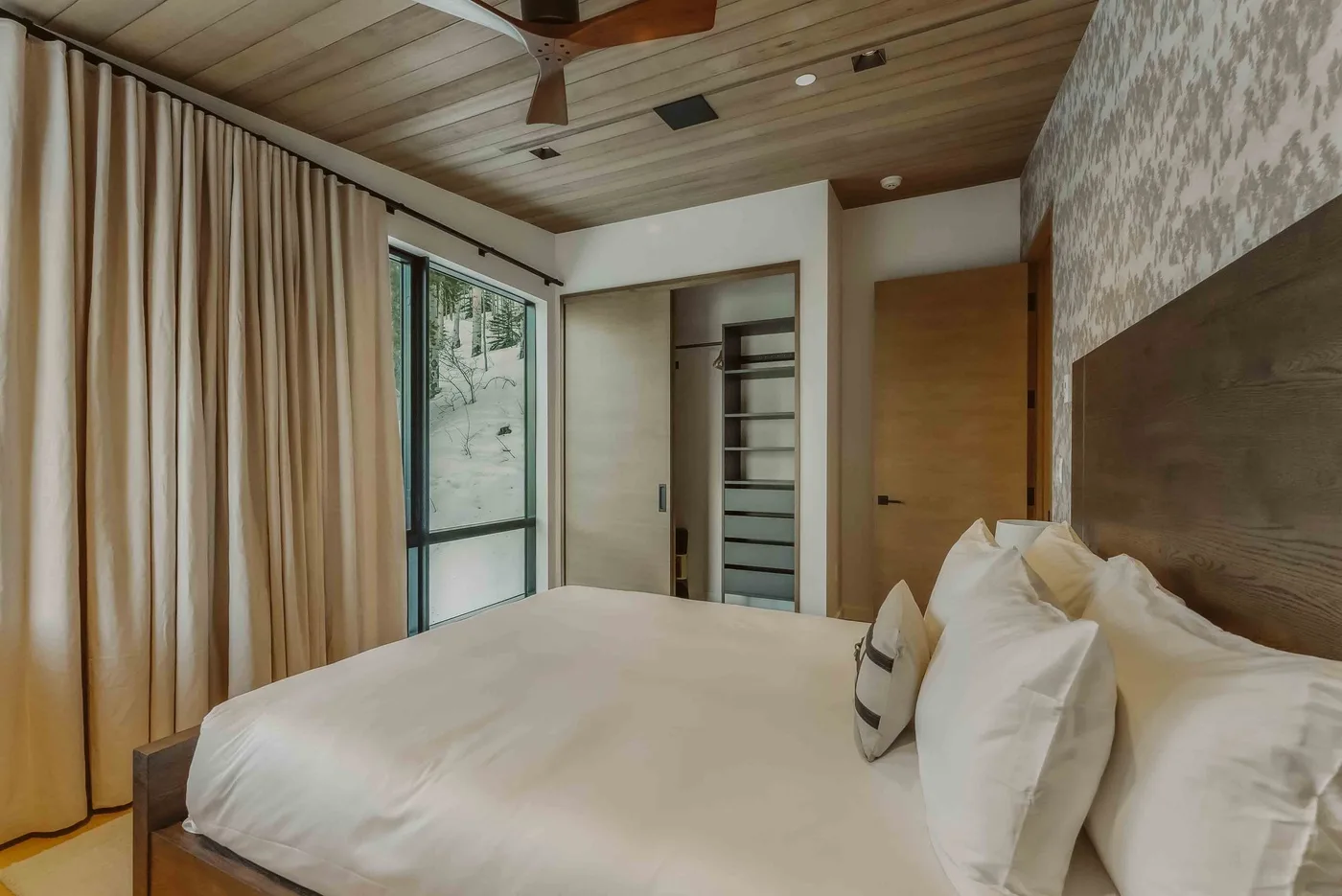 Un dormitorio con una cama junto a una ventana con cortinas.