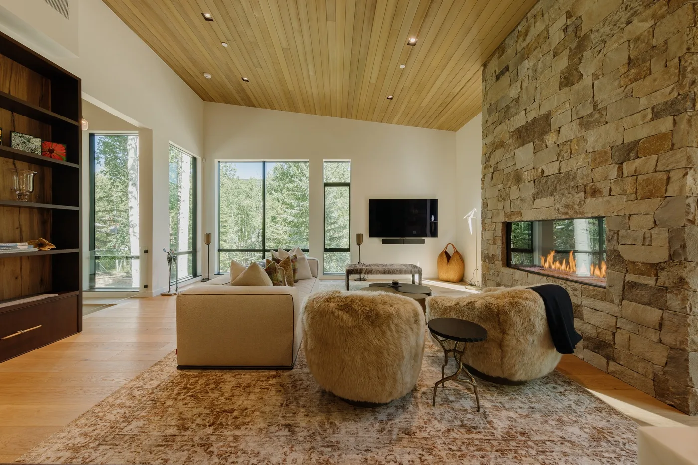 Una sala luminosa con grandes ventanas y una chimenea de piedra.