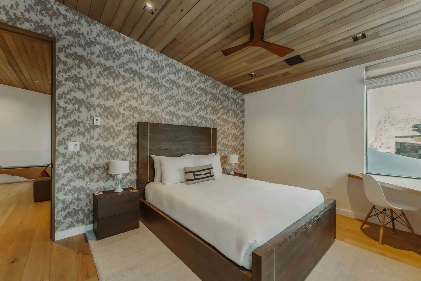 Un dormitorio con una cama, una mesita de noche y papel tapiz estampado.