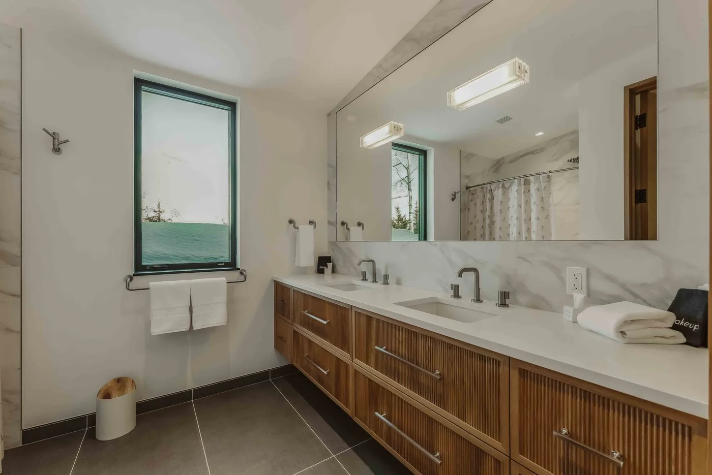 Un baño con un largo tocador, un gran espejo y una ventana con vistas al agua.