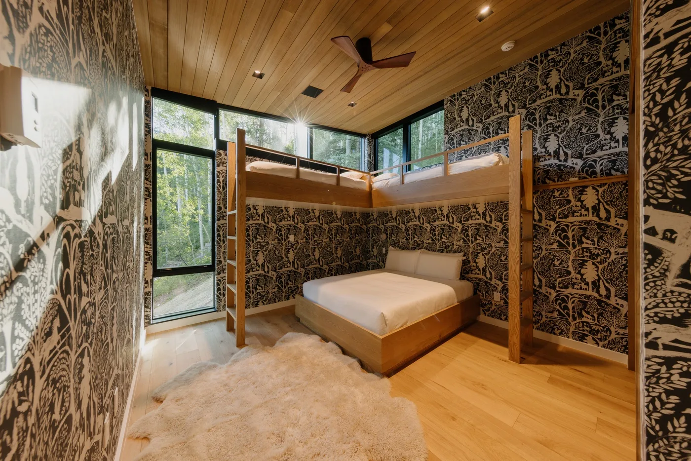 Un dormitorio con una cama elevada sobre otra cama y grandes ventanas.