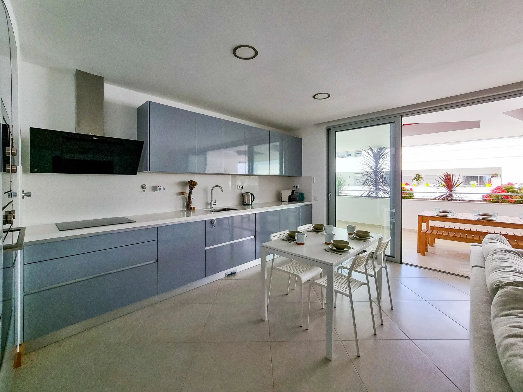 A modern kitchen and dining area open onto a terrace through sliding glass doors.