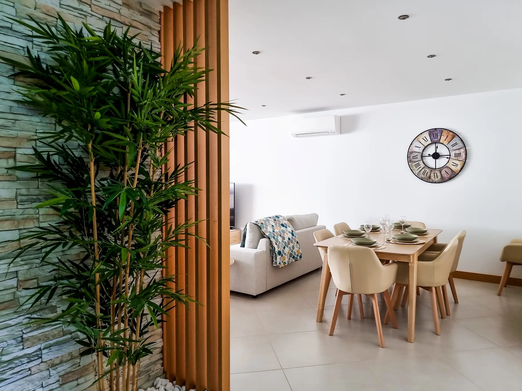A bright living and dining area with a table set beside a sofa.