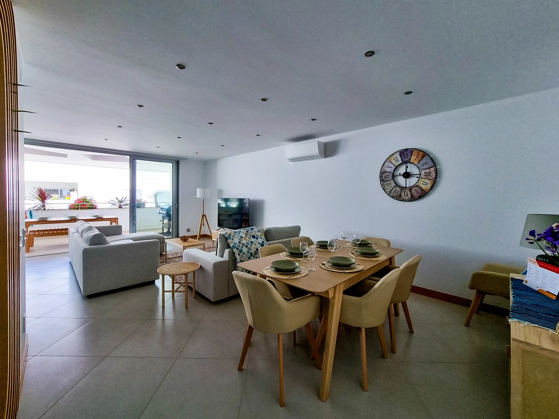 Un luminoso espacio de sala y comedor con asientos, una mesa y puertas corredizas de vidrio.