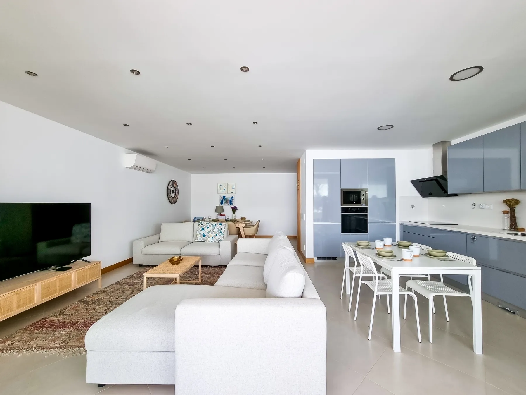 Open-plan living and dining area with seating, a television, and a kitchen.