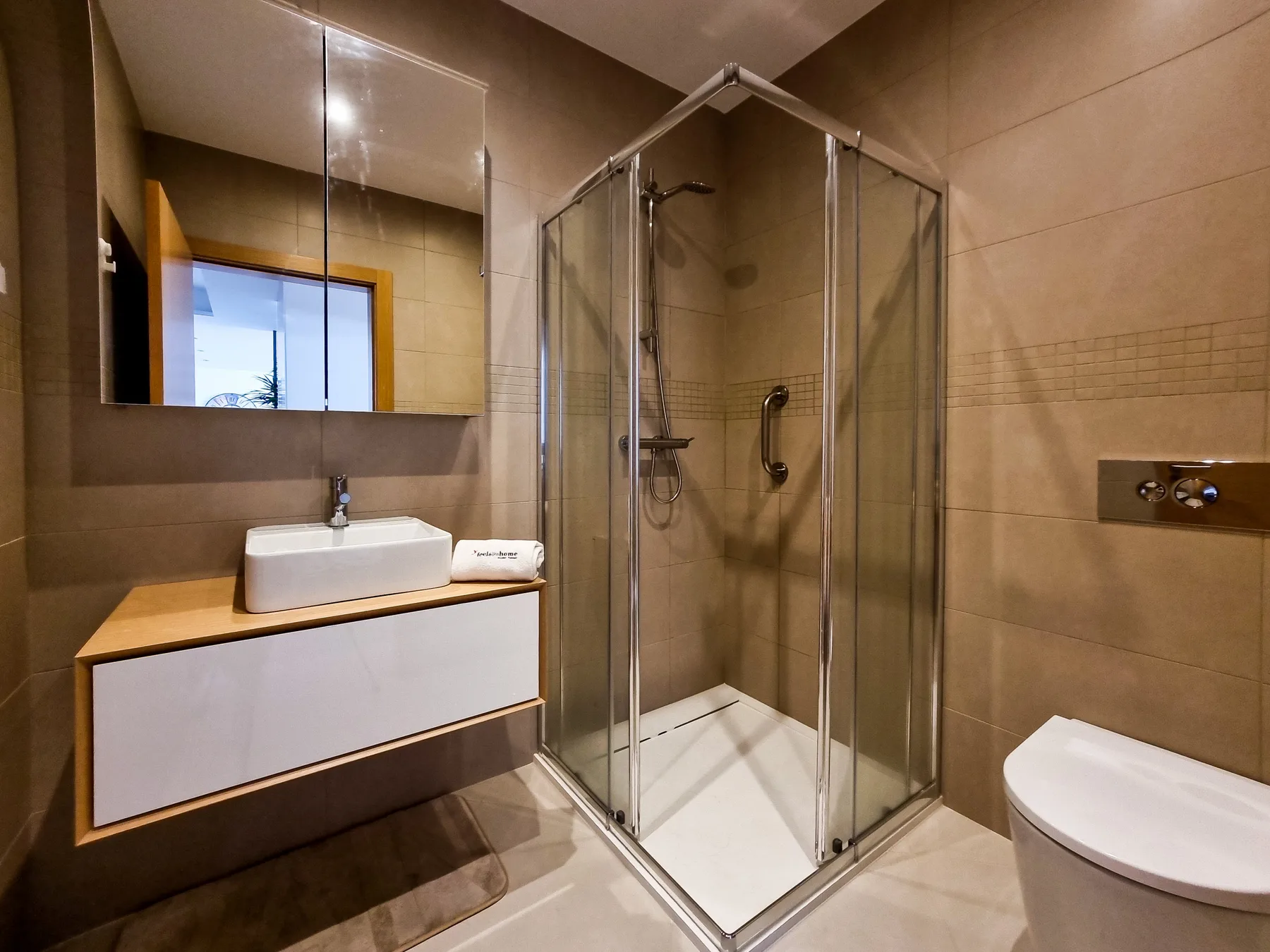 A modern bathroom with a glass shower, sink, and toilet.
