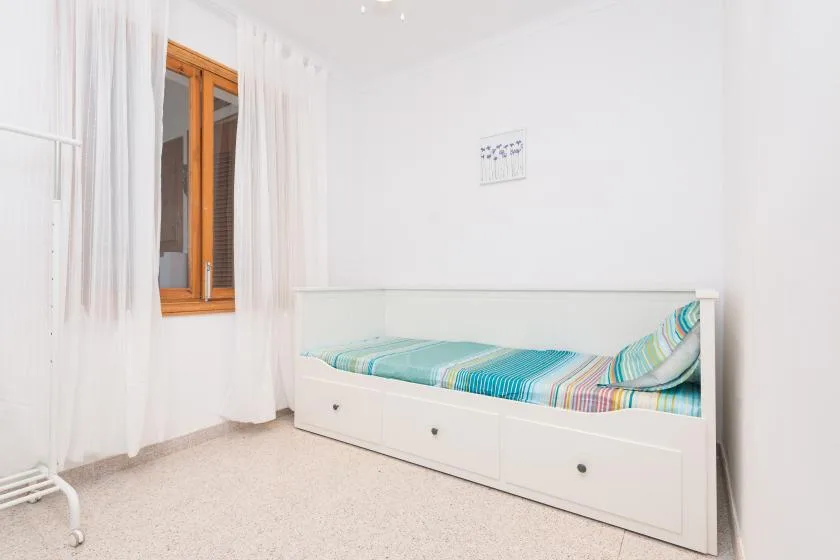 A bright bedroom with a white daybed and colorful striped bedding.