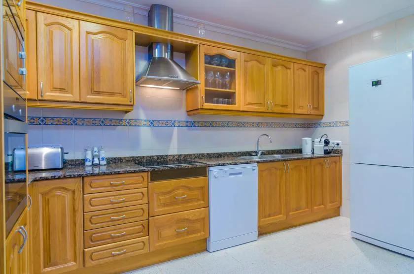 A kitchen with wooden cabinets, a countertop, and a refrigerator.