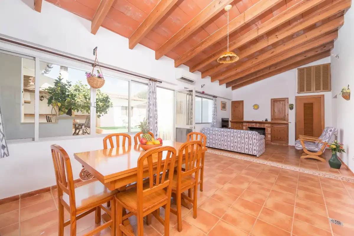 A dining area with a wooden table and chairs beneath exposed ceiling beams.