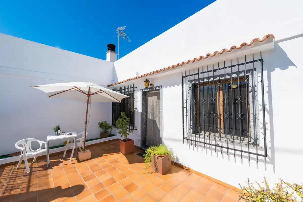 A sunlit tiled patio with outdoor seating and a large umbrella.