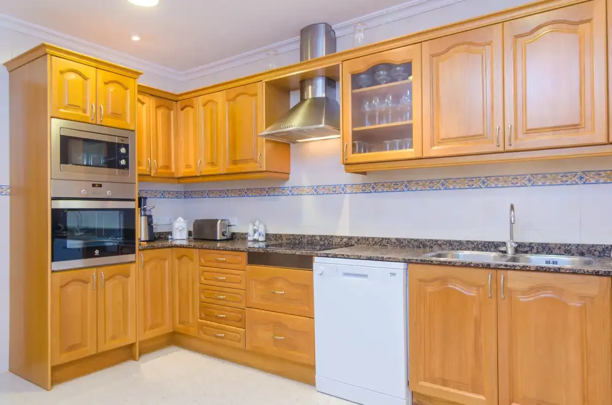 A kitchen with wooden cabinets, dark countertops, and built-in appliances.