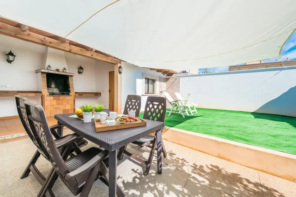 An outdoor dining area beside a brick barbecue and a green lawn.