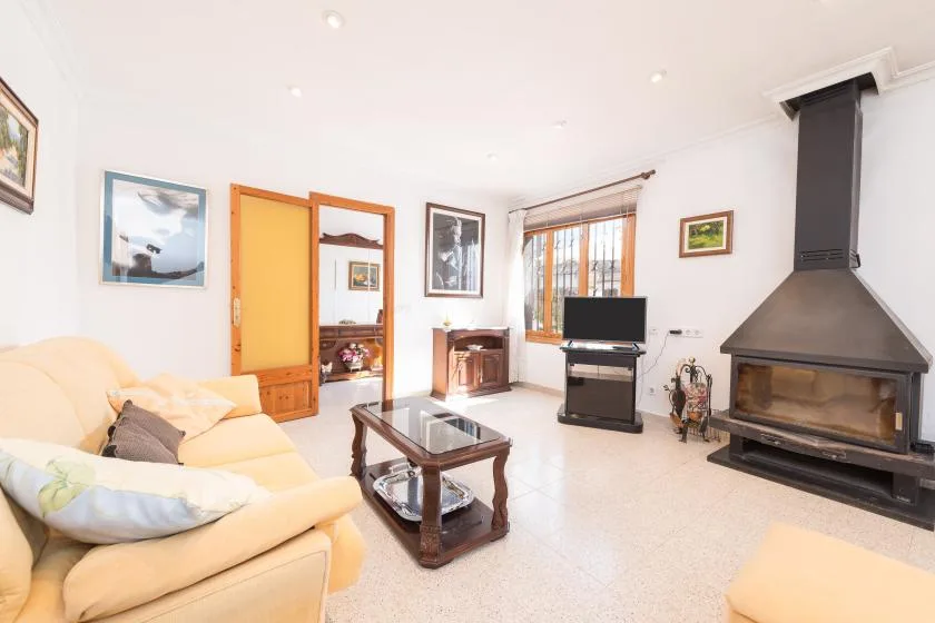 A bright living room with seating, a glass-topped coffee table, and a fireplace.