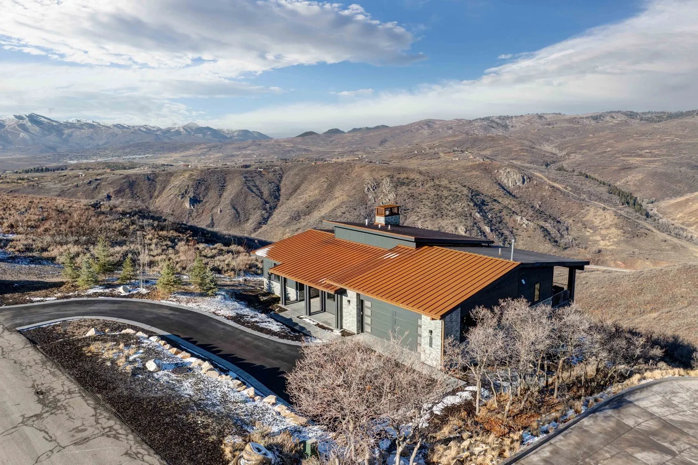 A modern building sits among rugged hills beneath a partly cloudy sky.