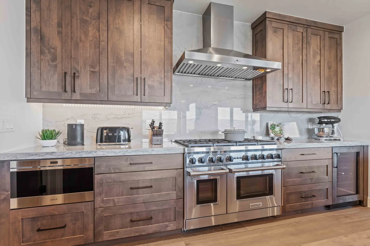 A kitchen with wooden cabinets, a range, and a stainless steel hood.