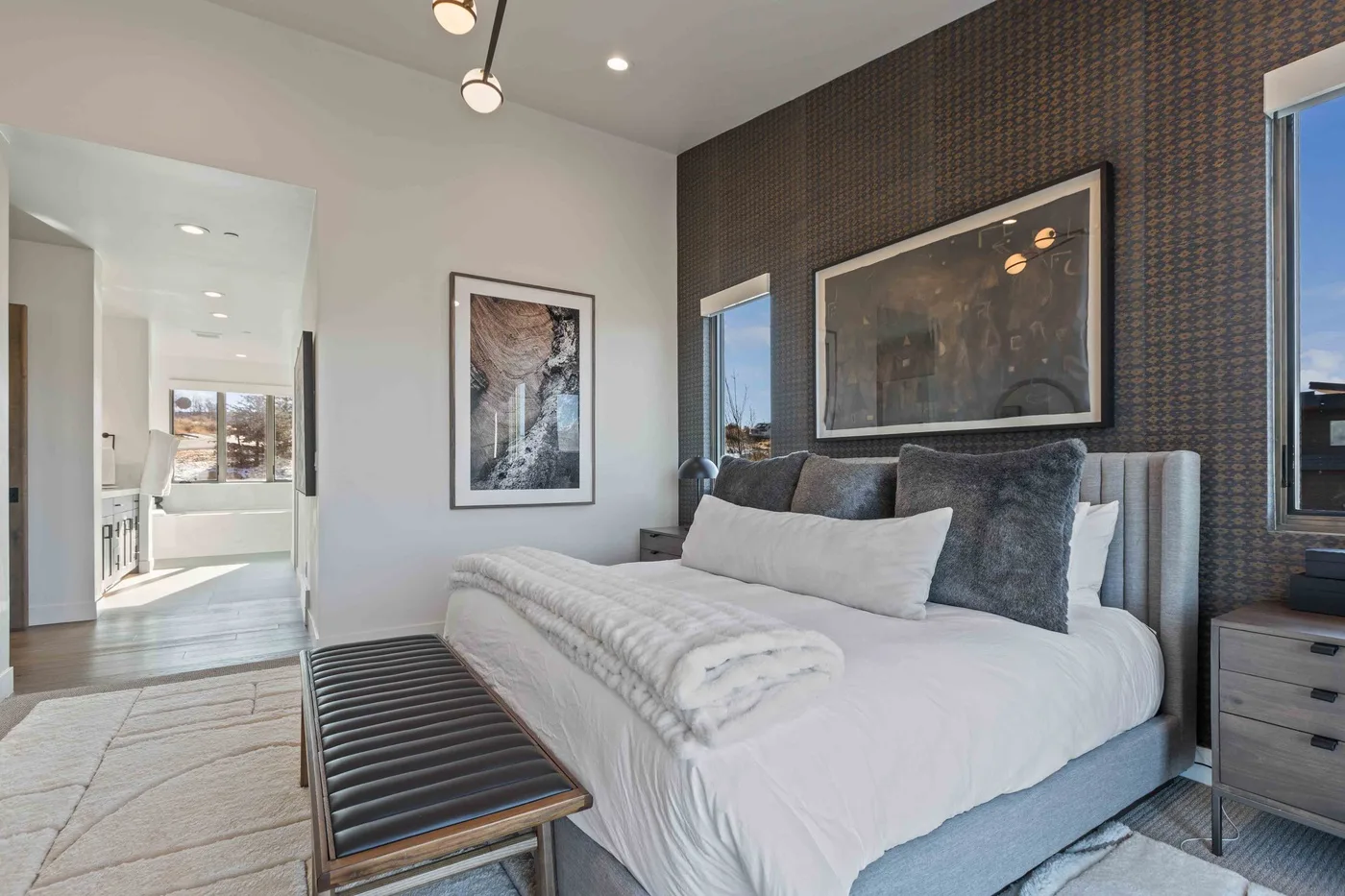 A bedroom with a neatly made bed, dark accent wall, and framed artwork.