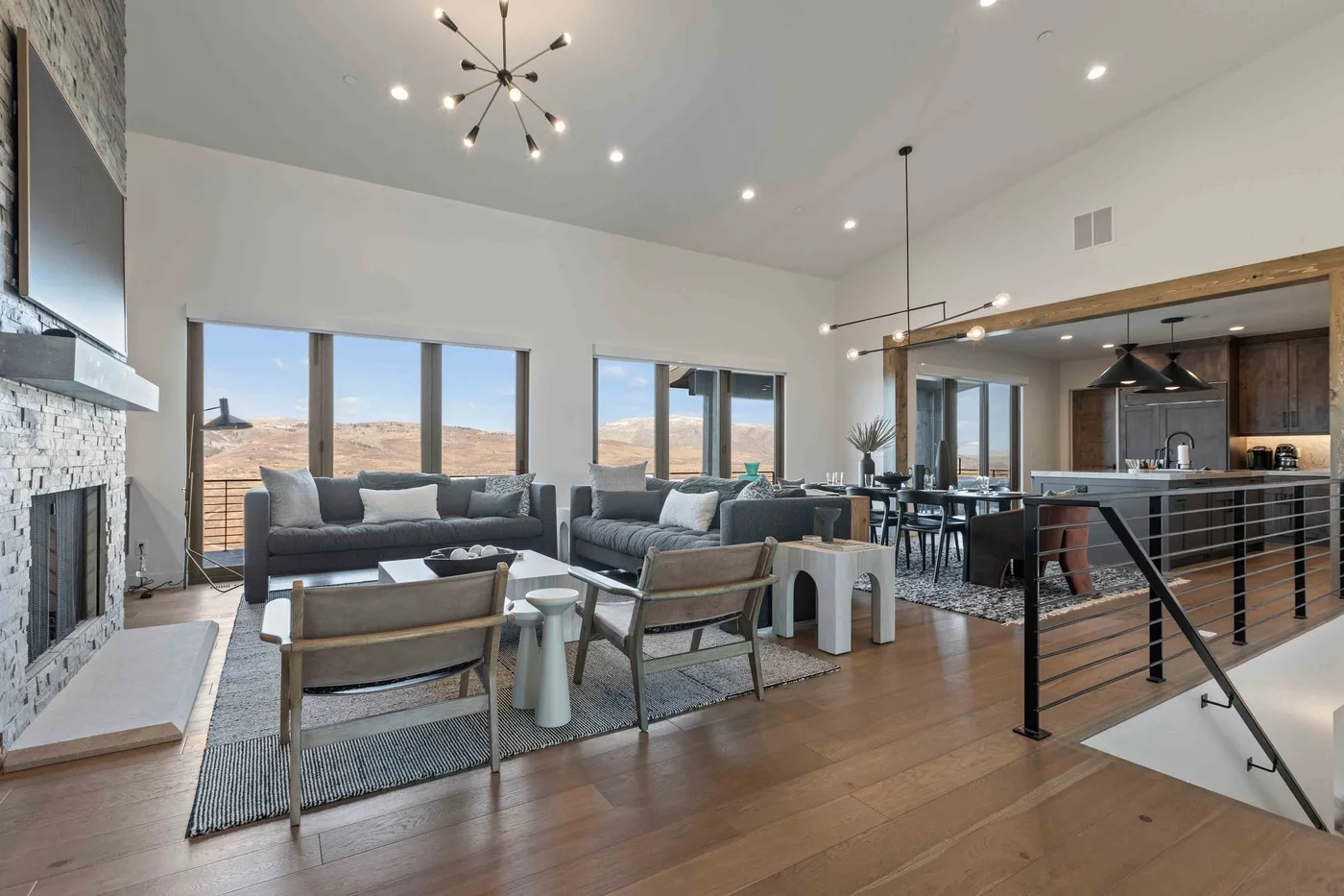 Open-plan living room and kitchen with seating, large windows, and a dining area.