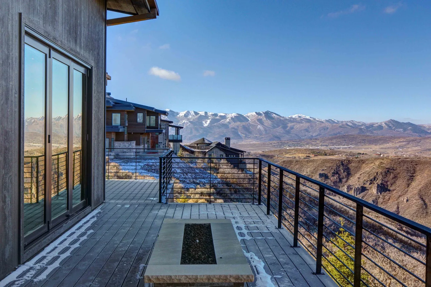 A tiled outdoor terrace with a metal railing overlooks a mountain valley.