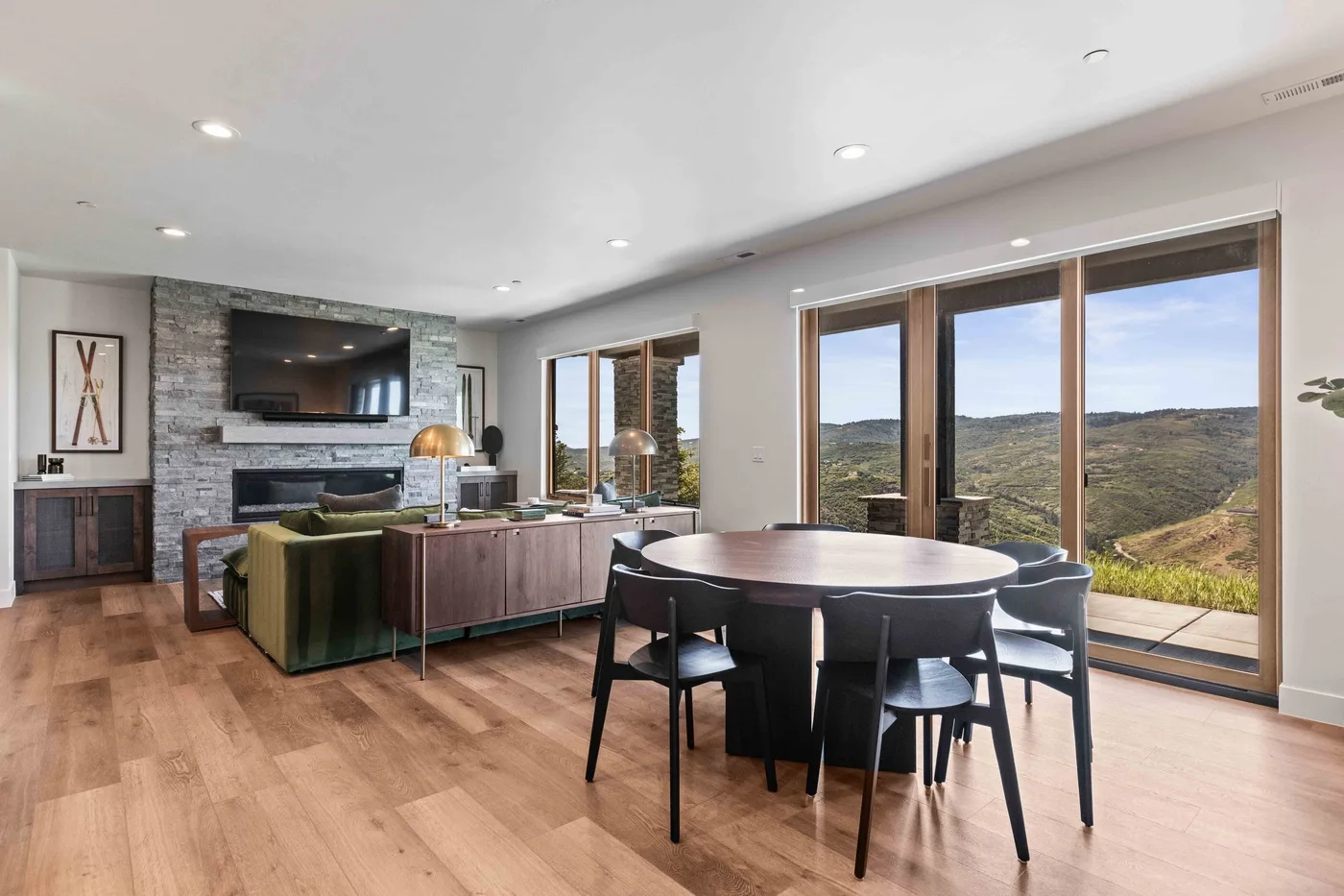An open living and dining area with seating, a dining table, and large windows.