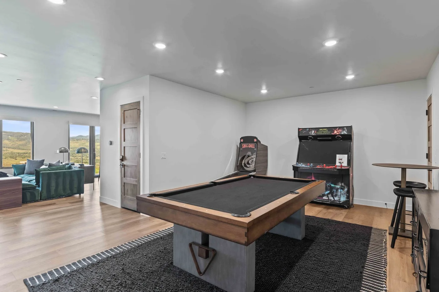 Una sala de juegos con una mesa de billar y una máquina recreativa.