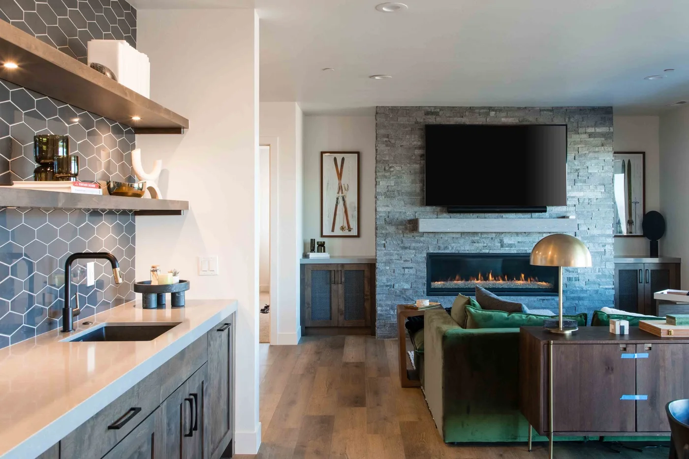 An open-plan living area beside a kitchen, with a television above a fireplace.