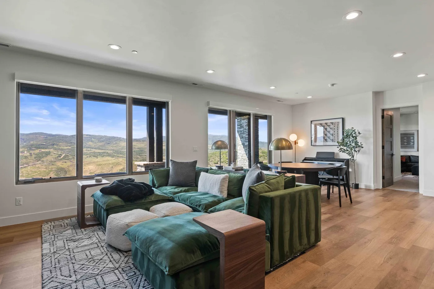 A bright living room with seating beside large windows overlooking a valley.