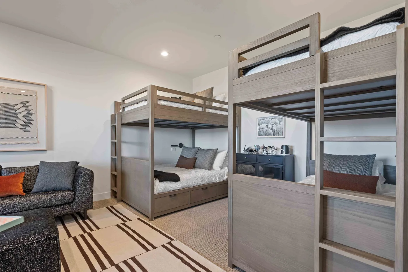 A bedroom with two bunk beds and a striped rug.