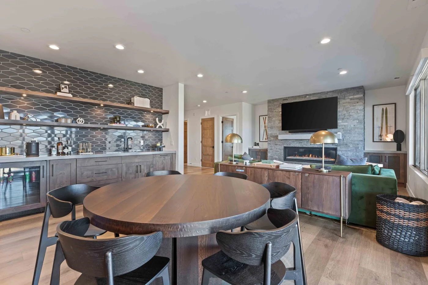 A dining and living area features a round table, seating, and a wall-mounted television.