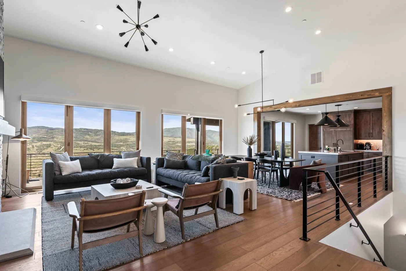 A bright open-plan living and dining area with large windows overlooking the landscape.