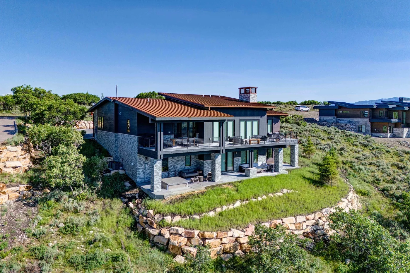 A modern house with a red-tiled roof and balconies stands among greenery.