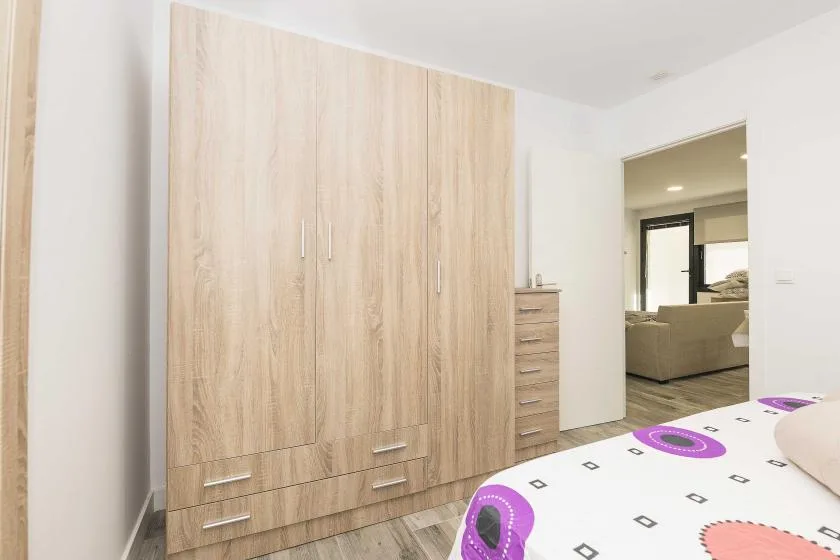 Un dormitorio con un gran armario de madera y una colcha estampada.