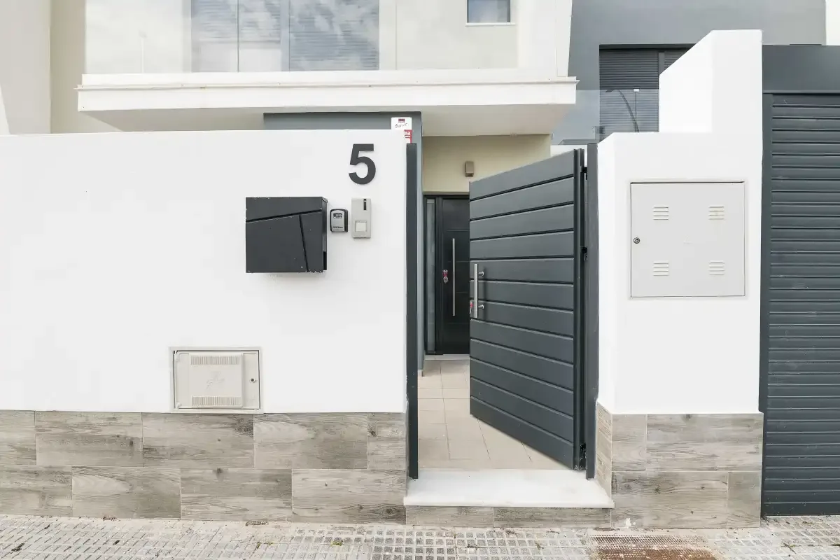 Entrada de un edificio moderno con una puerta oscura y paredes exteriores blancas.