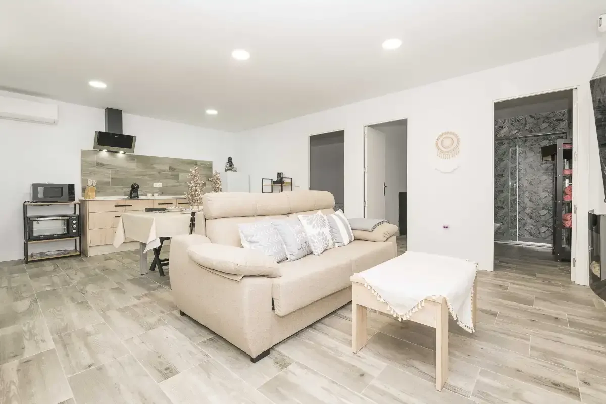 Una luminosa sala de estar con un sofá beige y una cocina abierta.