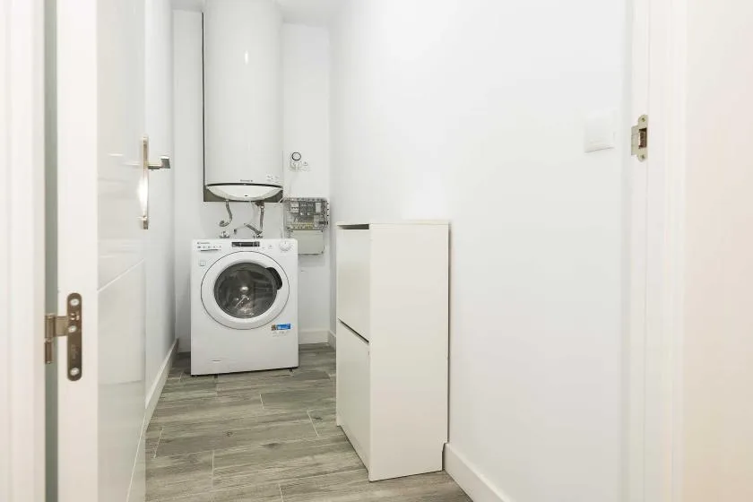 Una zona de lavandería con una lavadora debajo de un lavabo pequeño.
