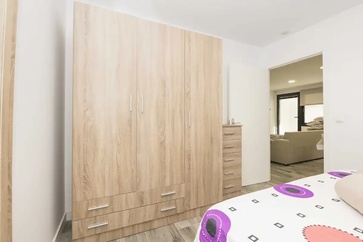 Un dormitorio con un armario grande de madera junto a una cama.