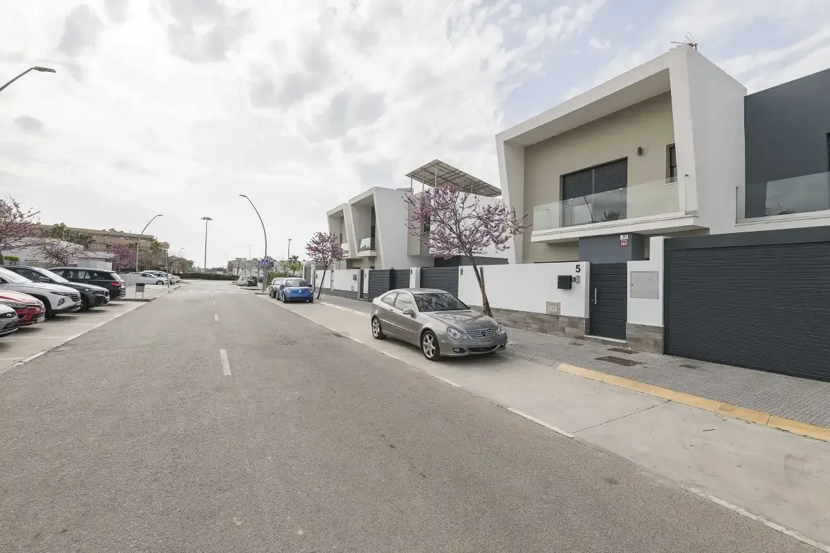 Una calle residencial bordeada de viviendas modernas y coches aparcados.