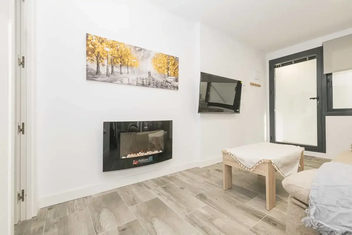 Sala de estar con televisor en la pared, chimenea y asientos.