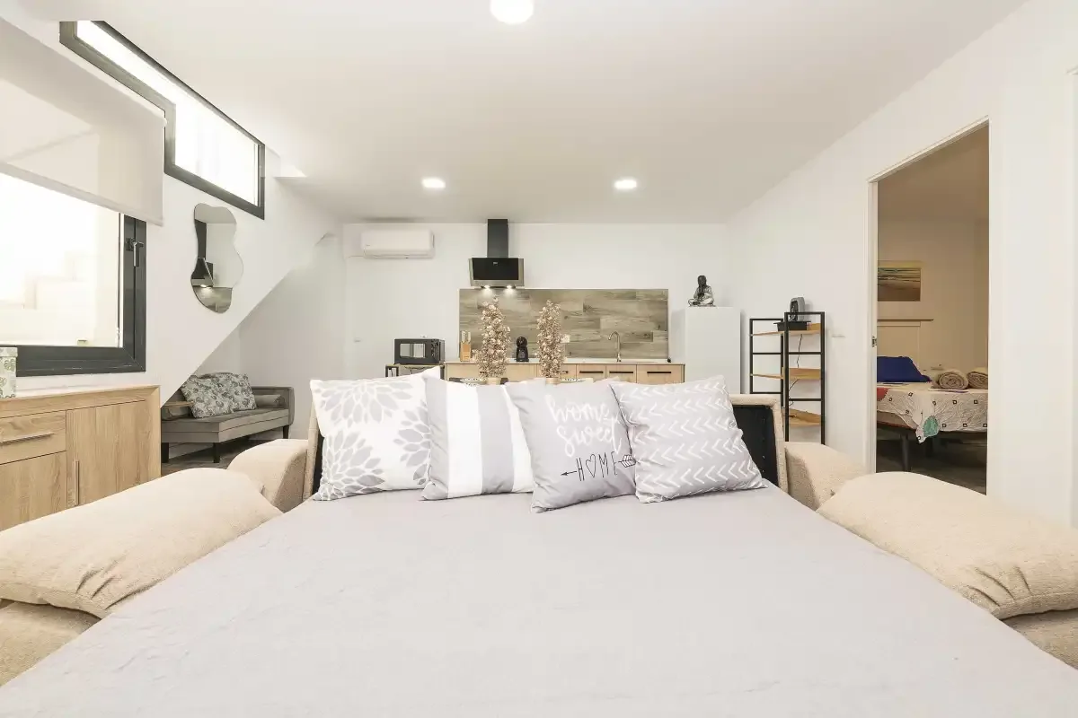 Un dormitorio con una cama grande y una pequeña cocina al fondo.