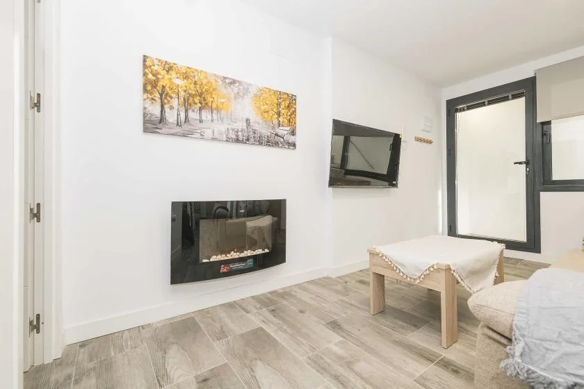 Una sala luminosa con pantallas en la pared y una mesa baja junto a los asientos.