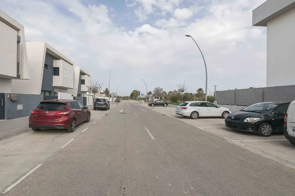 Una calle residencial con coches aparcados y edificios modernos de poca altura.