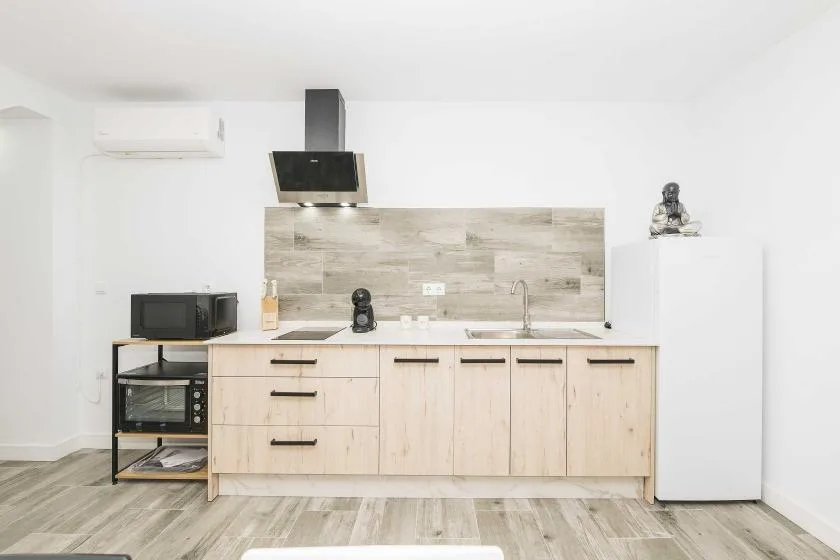 A bright kitchen with light wood cabinets, a countertop, and a refrigerator.