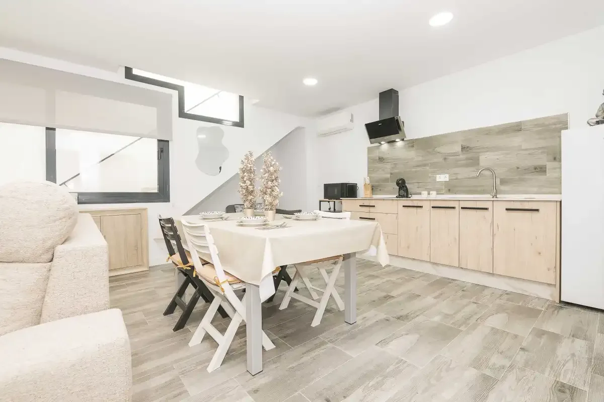 Una luminosa zona de comedor y cocina con una mesa junto a la encimera.