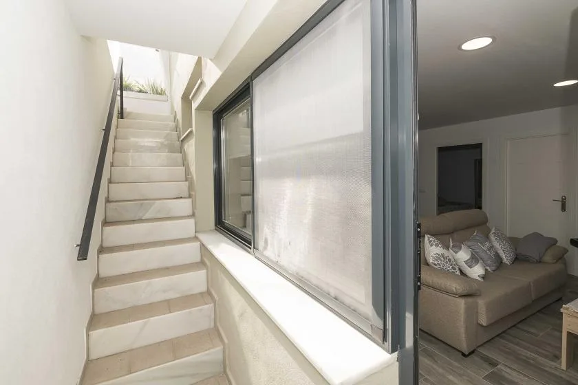 Una escalera junto a una ventana grande conduce a un rellano luminoso.