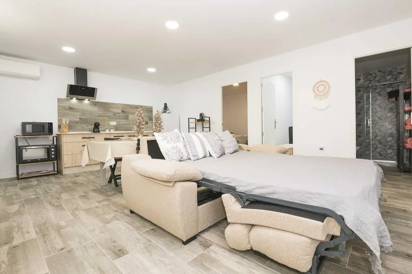 Un dormitorio con una cama grande y una pequeña zona de cocina al fondo.