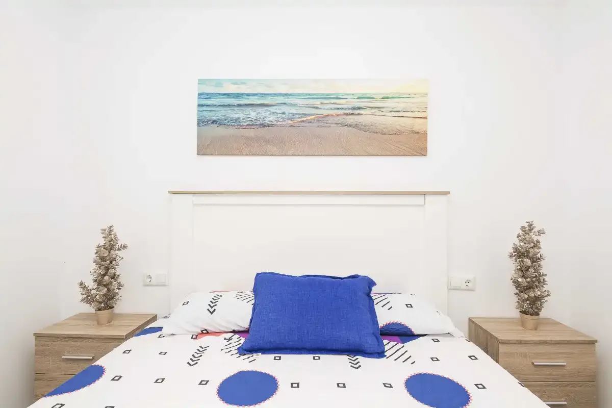 Dormitorio con una cama vestida con ropa de cama blanca y azul.