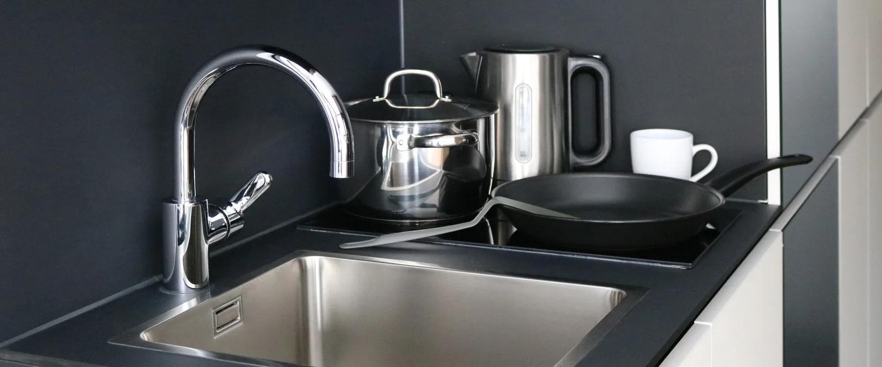 In-room cooking area with cooktop, sink and utensils