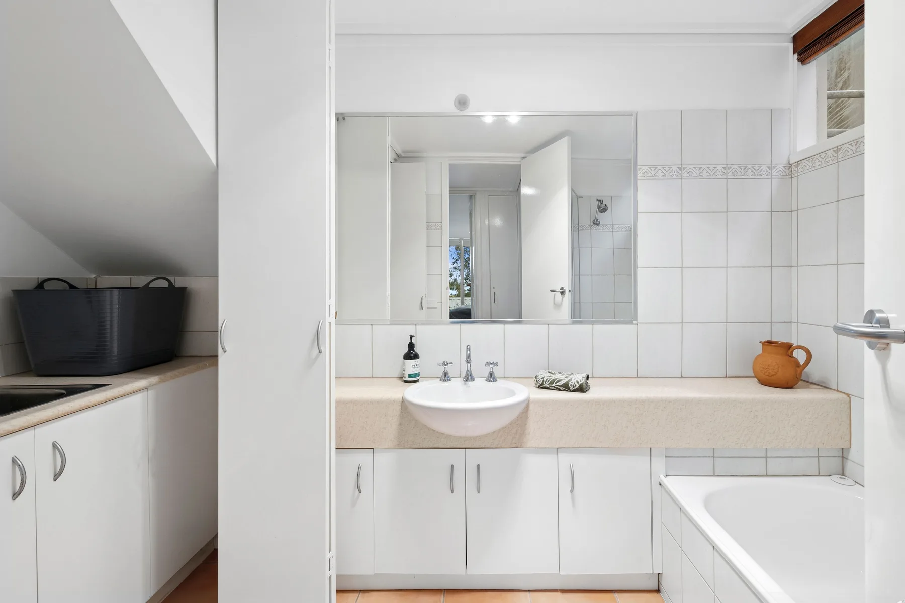Un baño luminoso con lavabo, espejo y bañera.