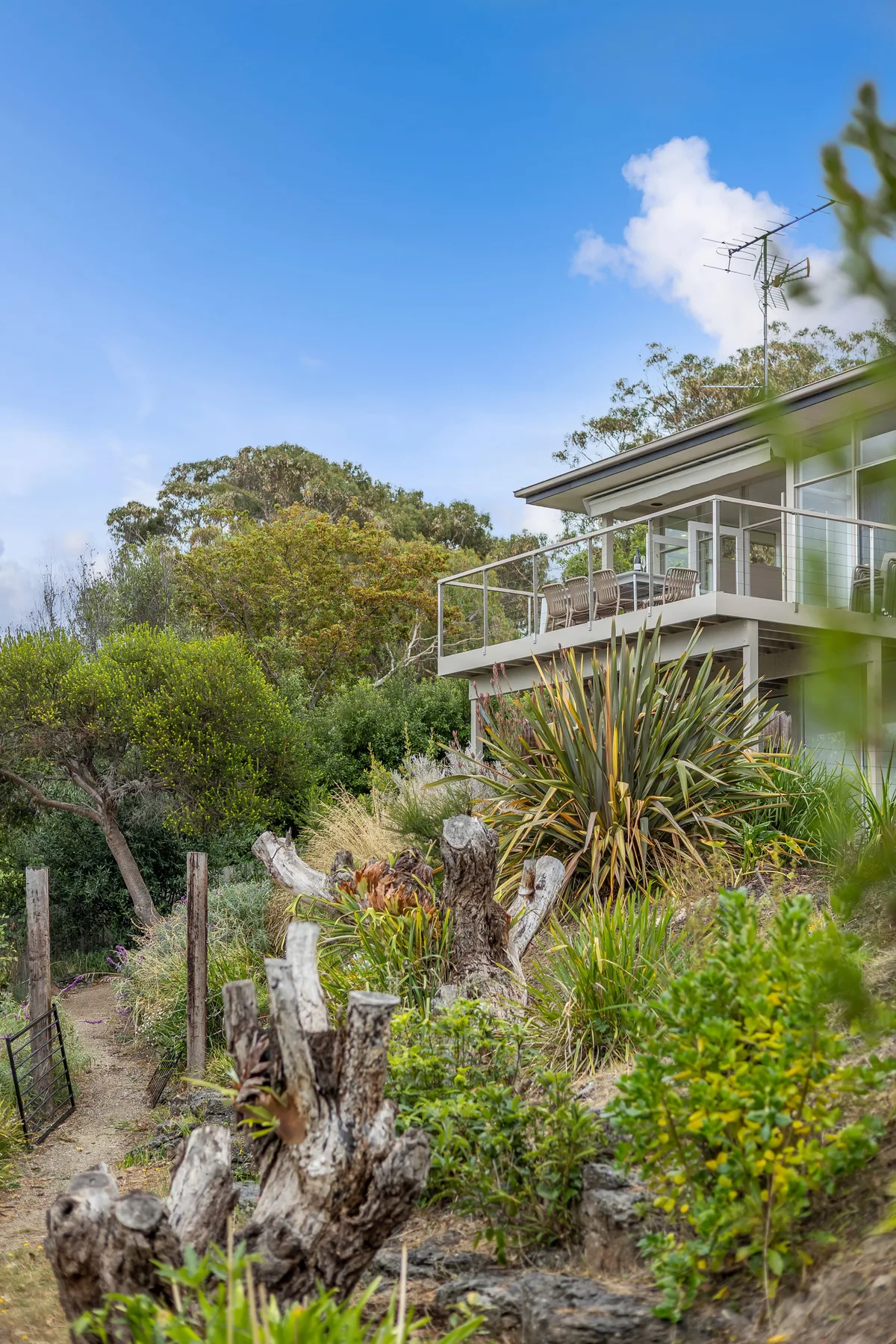 Una casa con un balcón elevado da a un jardín ajardinado.