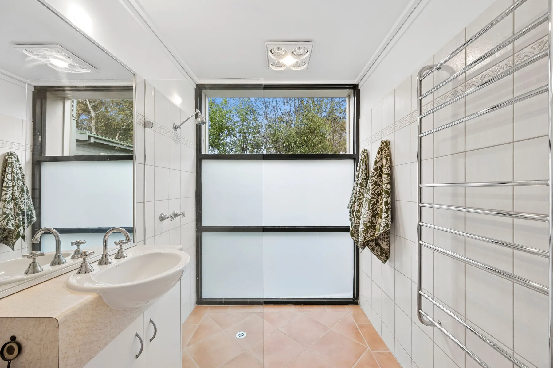 Baño luminoso con lavabo y una gran ventana esmerilada.